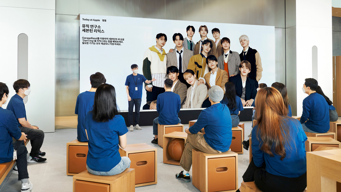 Klienci siedzący w audytorium przy ścianie wideo w Apple Myeongdong, nowym sklepie detalicznym Apple w Seulu.