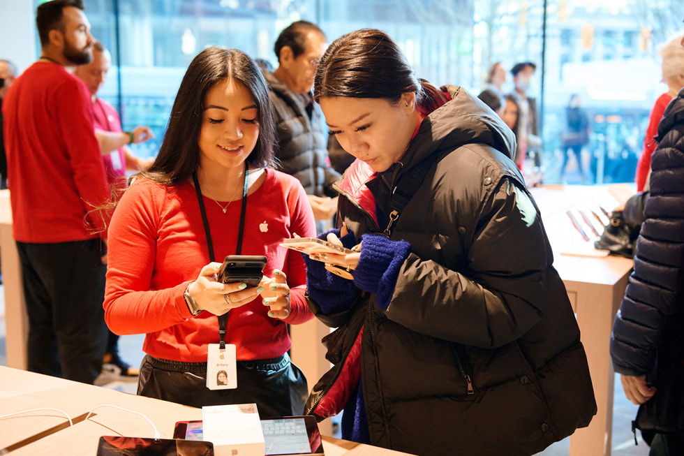 Des personnes montrent les produits qu’elles ont achetés à la nouvelle boutique Apple Pacific Centre de Vancouver, au Canada.