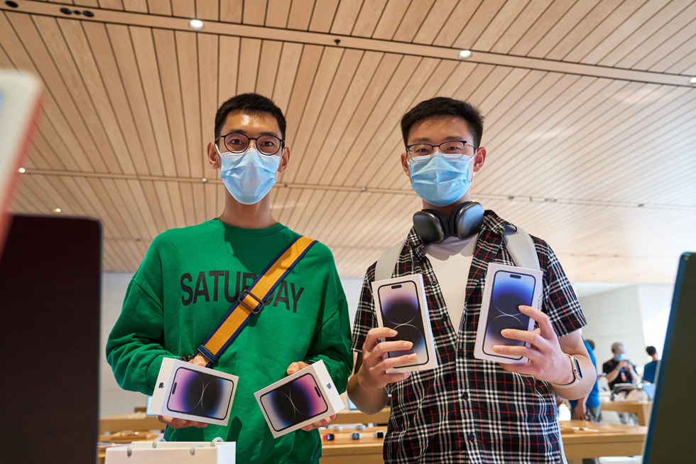 Two customers each holding two iPhone 14 Pro devices at Apple Sanlitun.