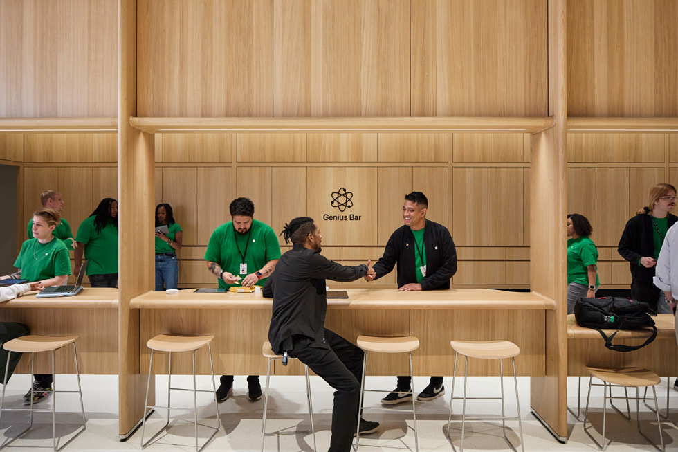 Customers are shown walking into Apple Tysons Corner while team members clap.