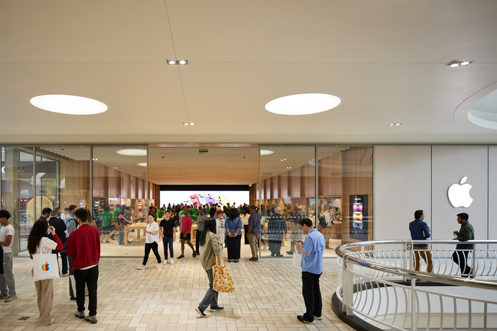 The storefront of Apple Tysons Corner is shown inside the mall, where customers congregate and mingle.