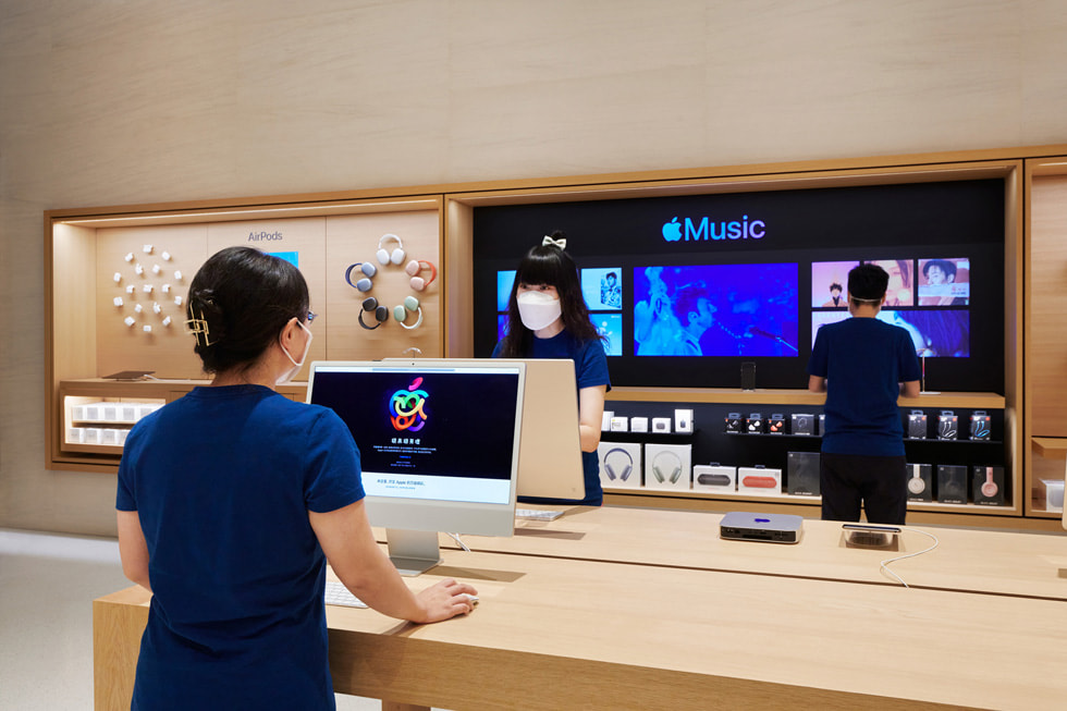 Mitarbeiter:innen des Retailteams an Tischen mit einem iMac in Apple Changsha.
