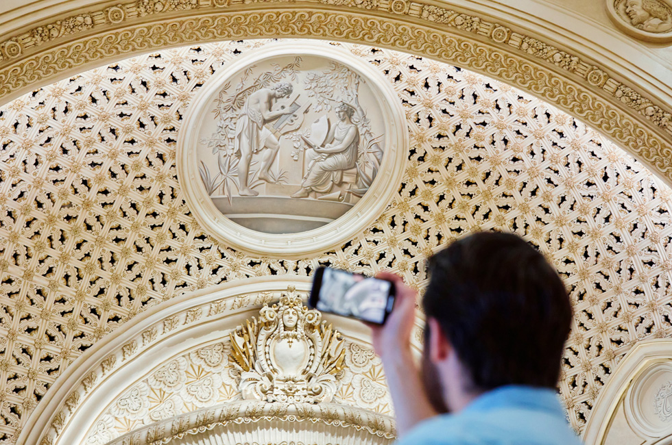 Ein Kunde macht mit einen iPhone ein Foto des detailgetreuen Dekors in Apple Tower Theatre.
