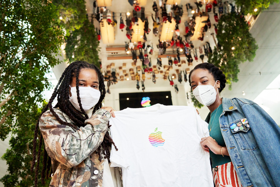 Deux personnes brandissant un t-shirt Apple à la boutique Apple The Grove.