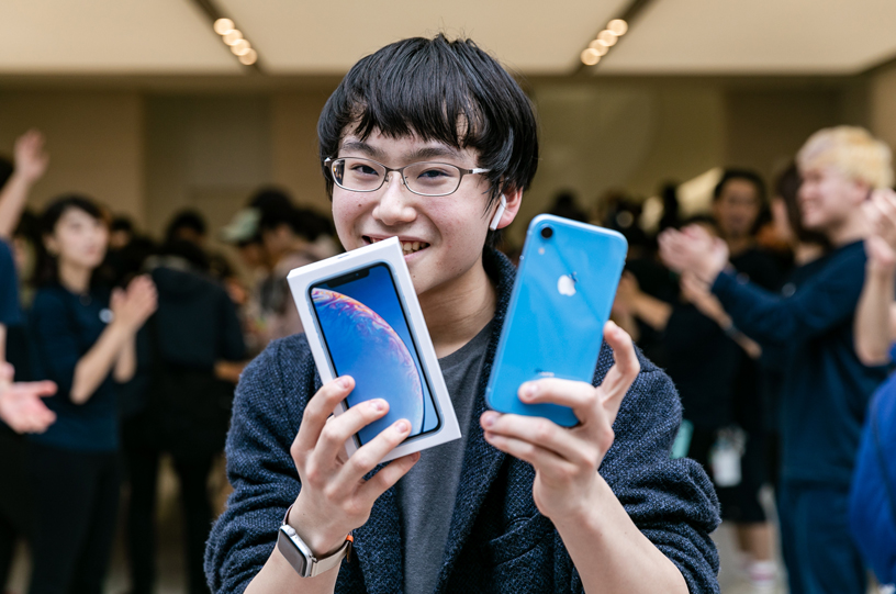 En kund håller upp en blå iPhone XR och låda.
