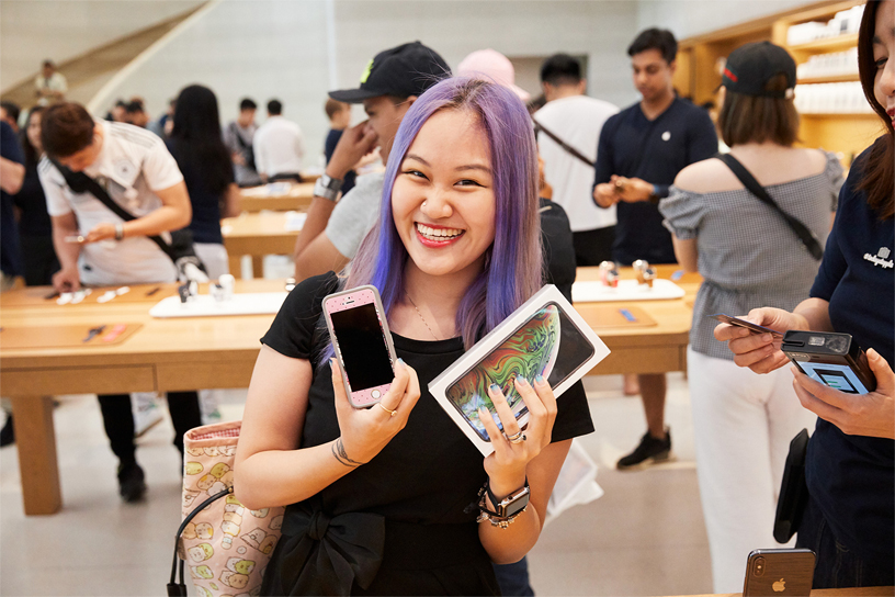 A young woman trading in an old iPhone for the new iPhone Xs Max.