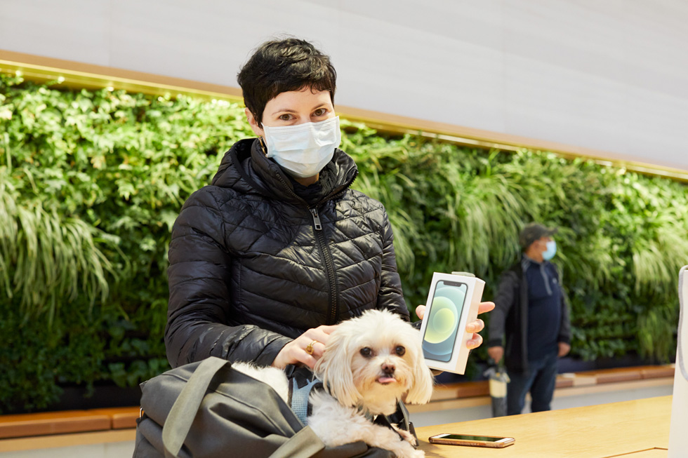 A customer and her dog holding her new iPhone 12 mini. 