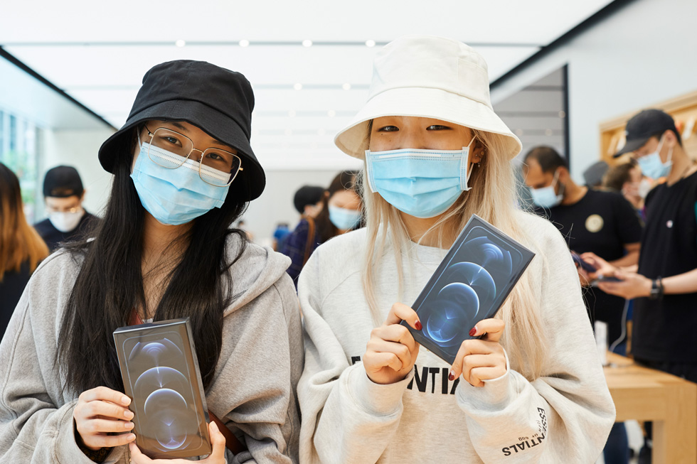 Customers at Apple Sydney show off their new iPhone 12 Pro Max purchases.