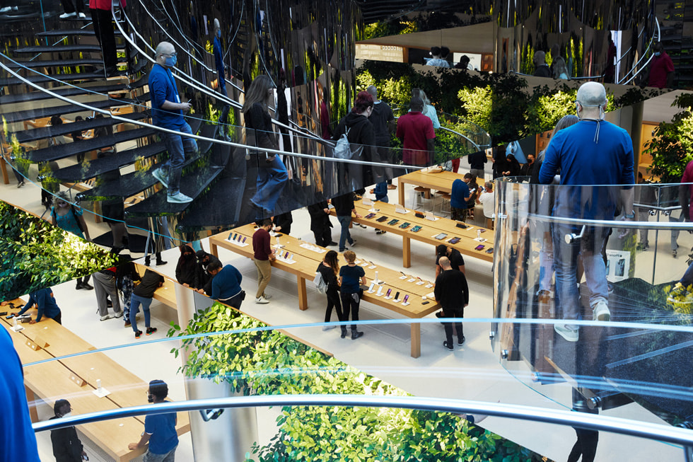 Uitzicht vanaf de trap op de producttafels van Apple Fifth Avenue, waar klanten en medewerkers rondlopen.