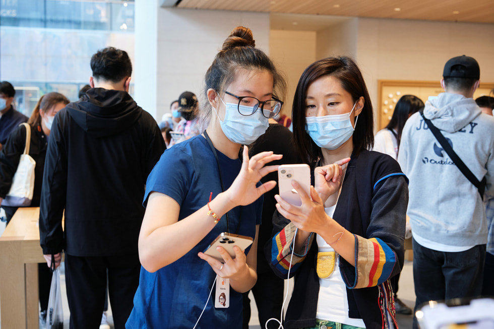 A team member at Apple Sanlitun helps a customer with iPhone 13.