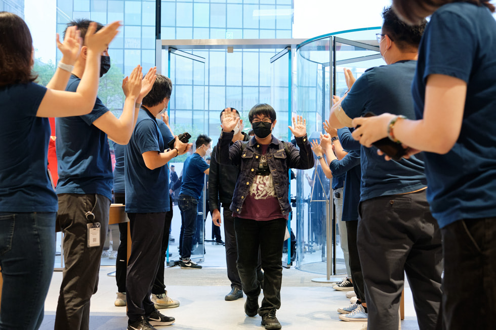 Los miembros del equipo del Apple Sanlitun saludan a los clientes que llegan en busca de la línea del iPhone 13.