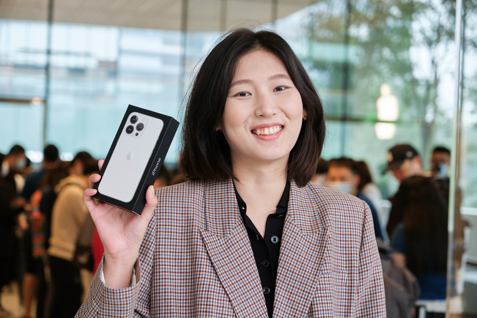 Une cliente prend la pose avec l’iPhone 13 Pro à l’Apple Sanlitun.