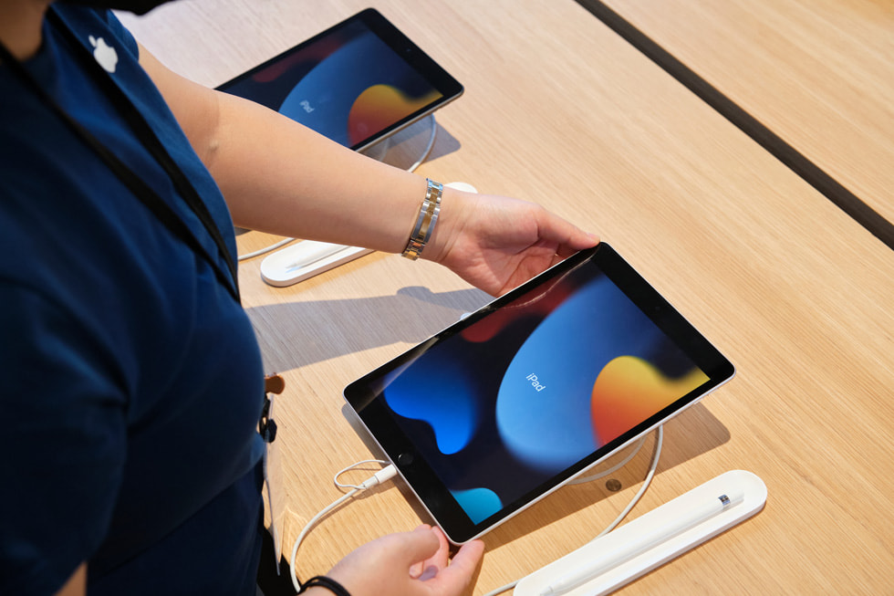 Ein Teammitglied von Apple Sanlitun richtet einen Anzeigetisch für das iPad der neunten Generation ein.