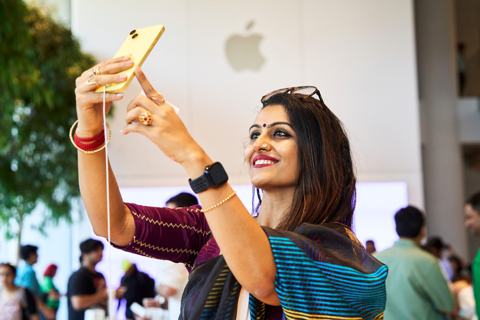 Eine Kund:in macht ein Selfie mit dem gelben iPhone 14.
