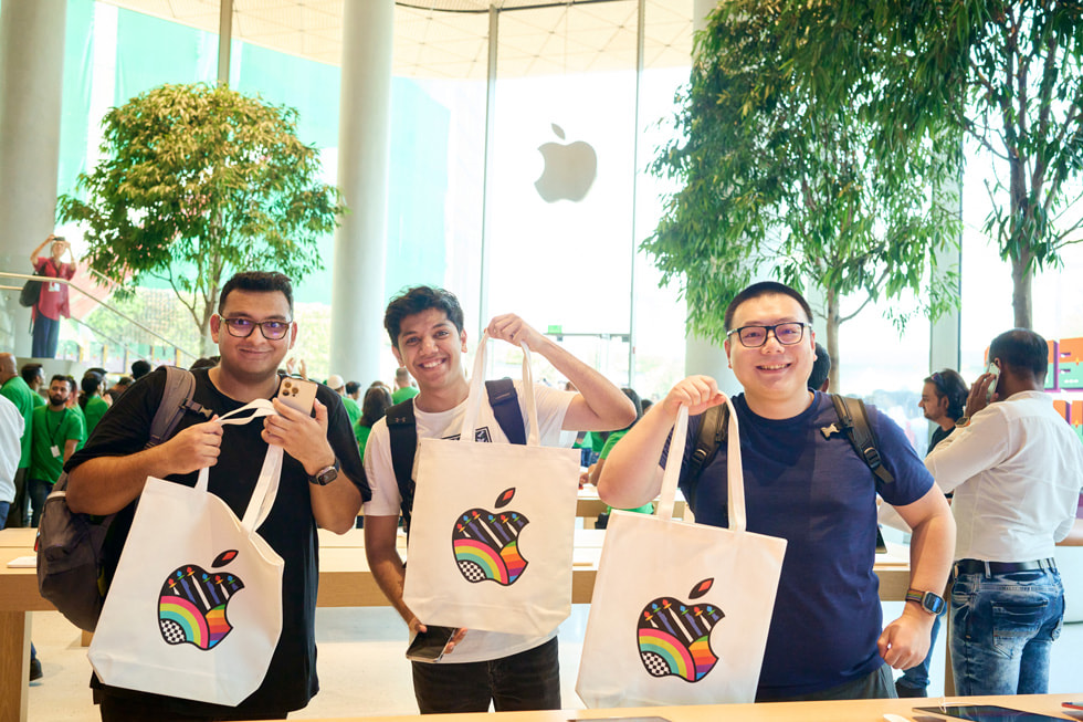 Customers pose with an Apple-branded tote bag. 