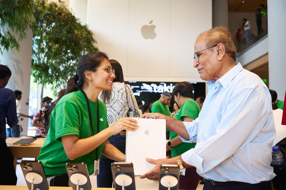 An Apple BKC team member presents a customer with his purchase. 
