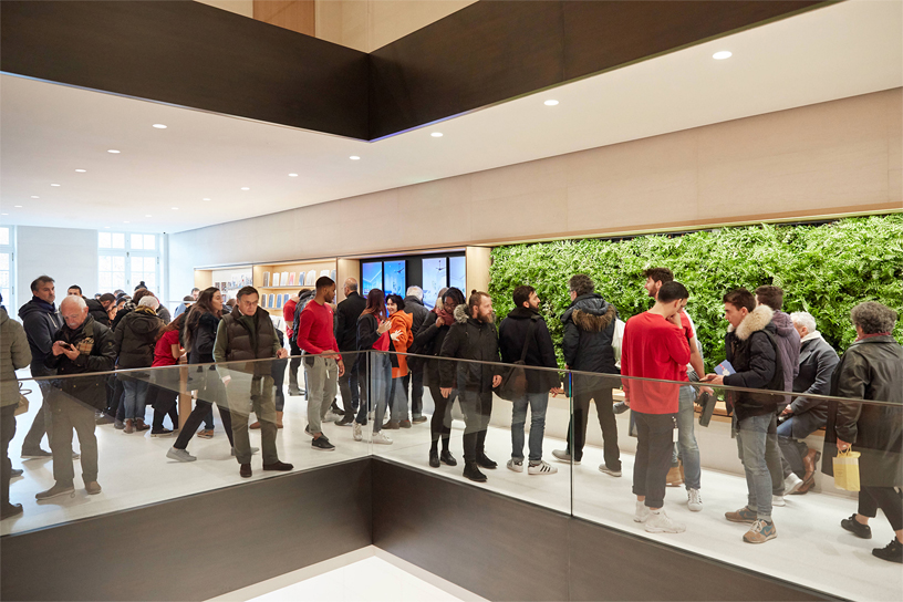 Team members and customers standing in front of a green wall at Apple Champs-Élysées.