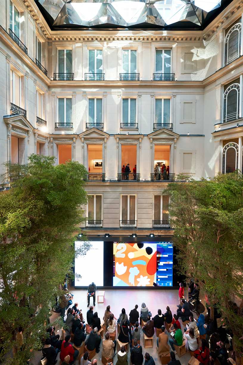 A crowd of customers sitting in the Forum at Apple Champs-Élysées.