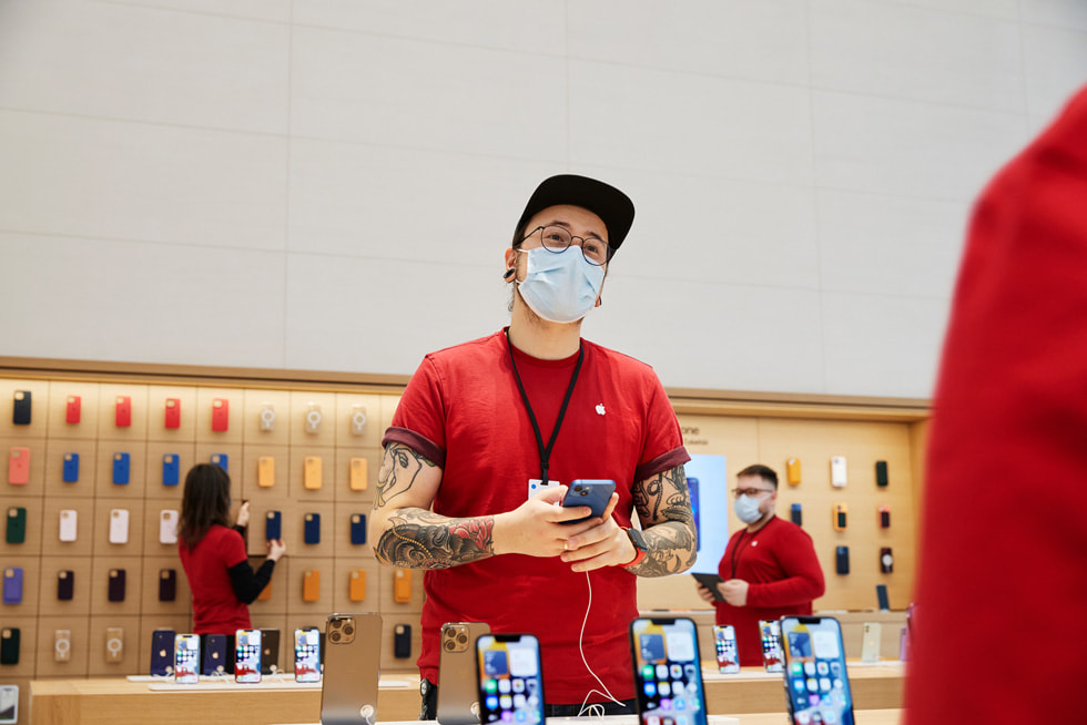 Uma pessoa da equipe da Apple Rosenthaler Straße prepara as mesas de exibição do iPhone.