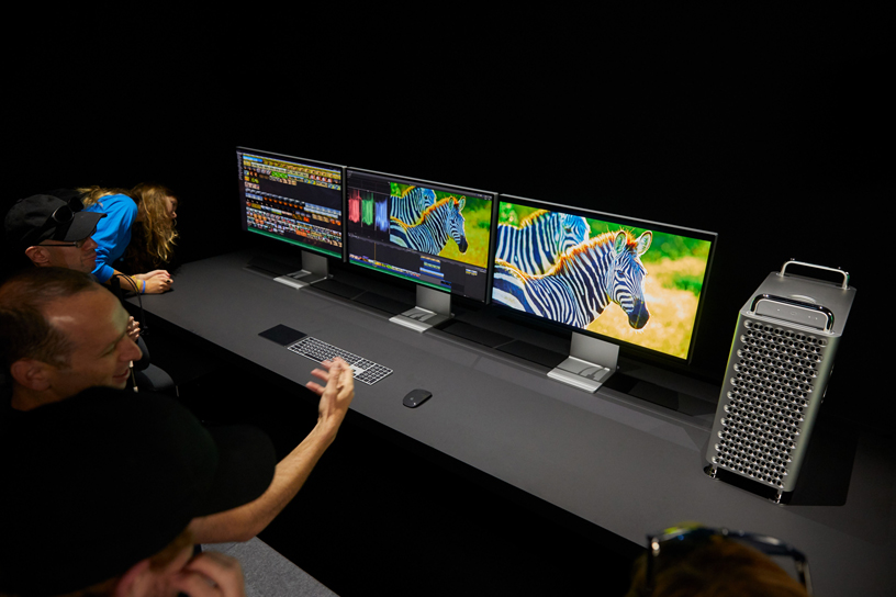Convidados da WWDC observam três telas Pro Display XDR ao lado do Mac Pro.