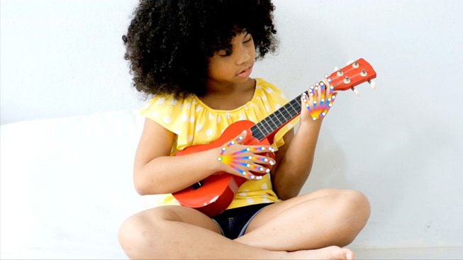 A child playing a Ukulele to demo hand pose detection.