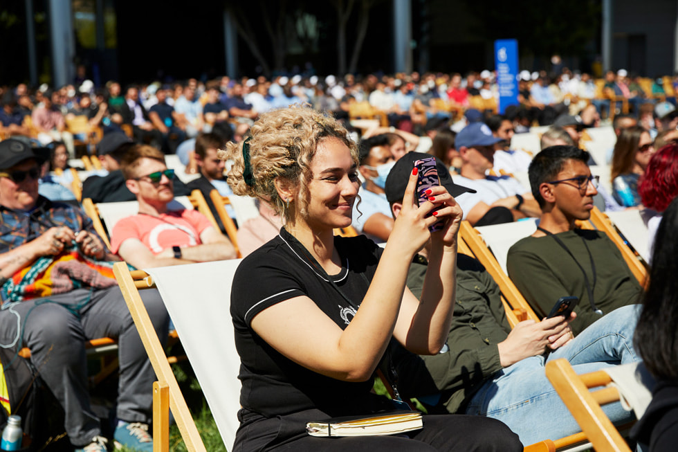 Apple ParkのCaffè Macsの外でWWDC22の基調講演を観る参加者。