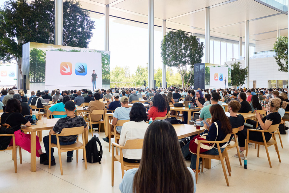 Studenti e studentesse alla WWDC22 guardano una presentazione di SwiftUI.