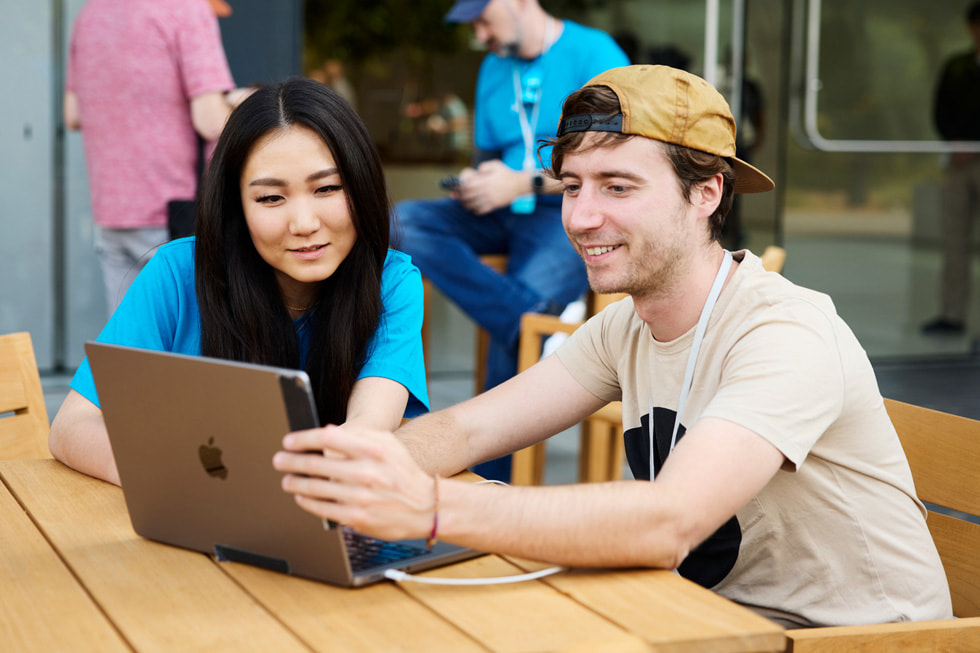 WWDC23 的 Meet the Developers 活動中，兩個人看著一台 MacBook。