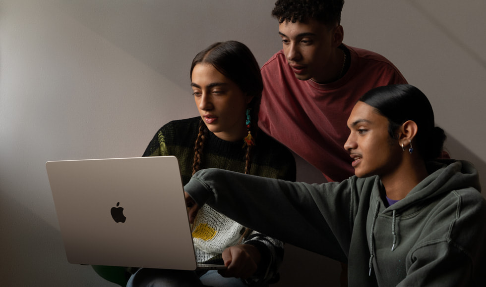 صورة تُظهر ثلاثة أشخاص ينظرون إلى جهاز MacBook Air مقاس 15 إنش.