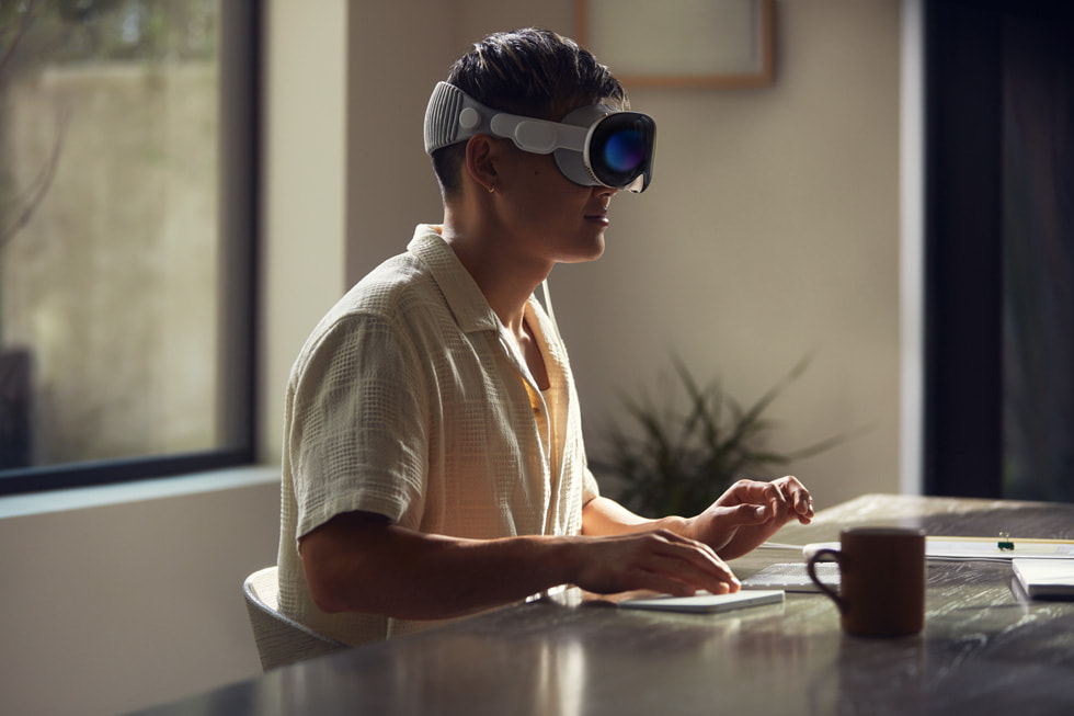 A person working with Apple Vision Pro and their computer.