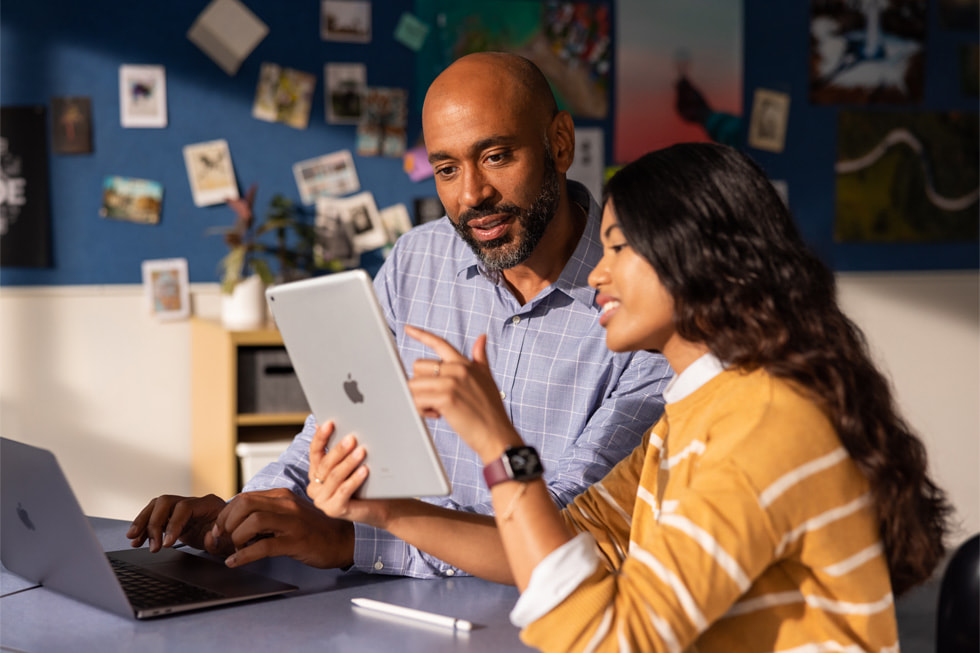 Een leerkracht coacht een collega met behulp van een iPad en MacBook Air.