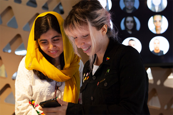 Malala Yousafzai looks at an iPhone with a woman at the Apple Developer Academy in Rio.