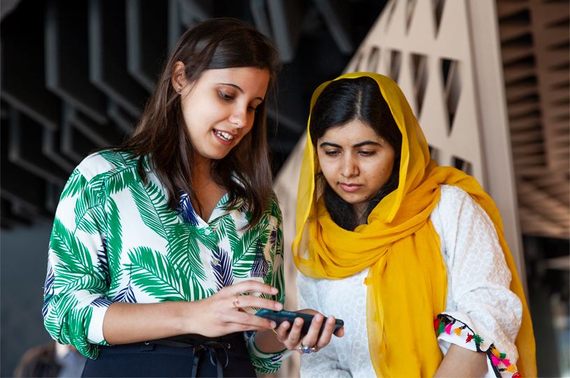 Malala Yousafzai looks at an iPhone with a woman at the Apple Developer Academy in Rio.