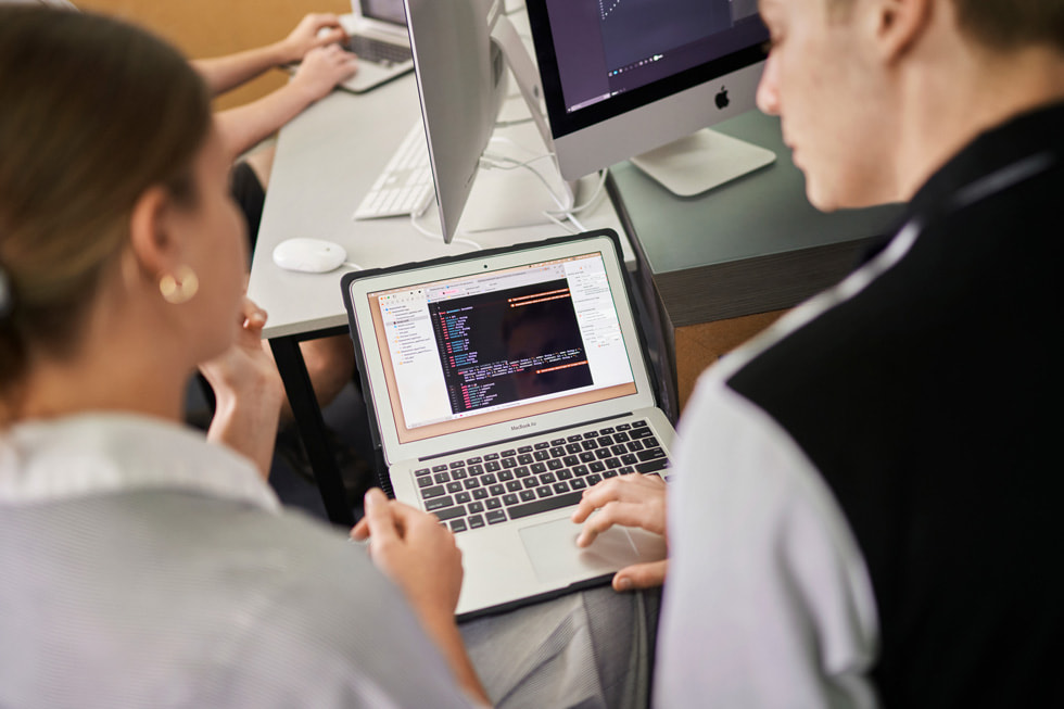 Siena Catholic College 學生與教師在 MacBook Air 上檢視程式碼。