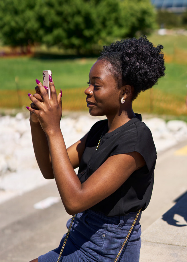 Adetokunbo Opeifa segura o iPhone para tirar uma foto no parque.