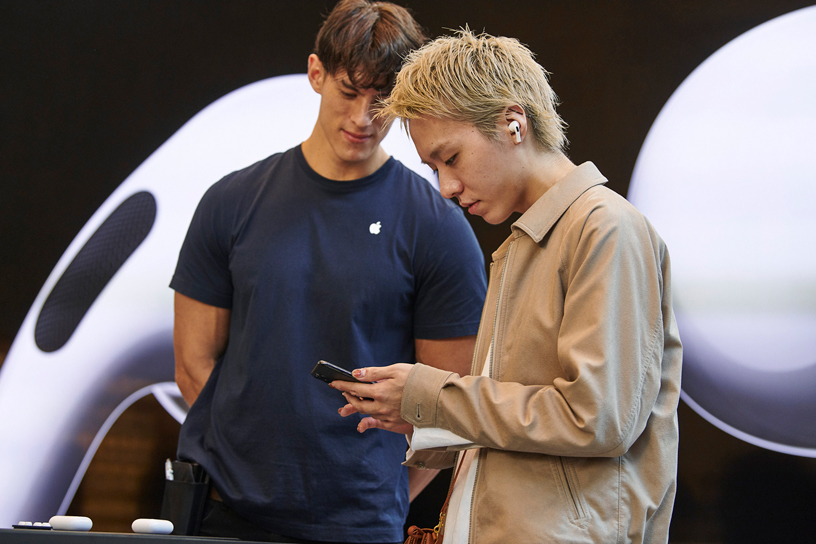 An Apple team member watches a customer try out AirPods Pro.