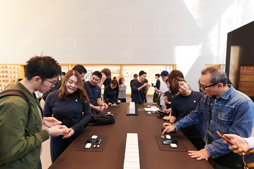 Apple team members assist customers around a table at Apple Omotesando in Tokyo.