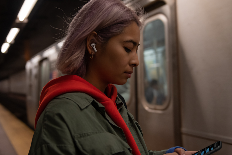 Una persona ascolta musica con gli AirPods Pro mentre aspetta il treno.