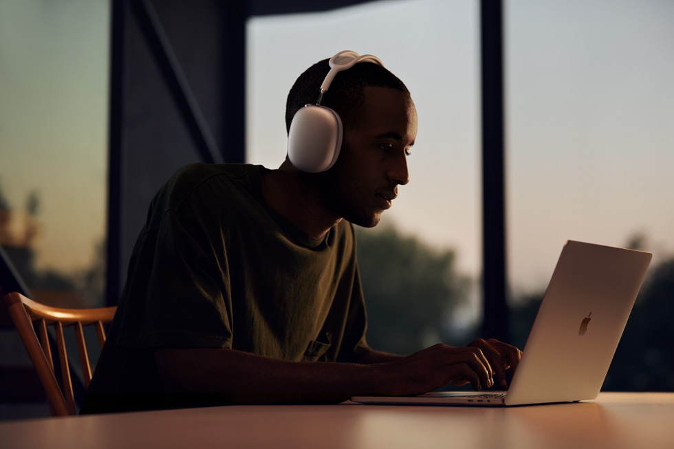 Man using AirPods Max with MacBook Pro.