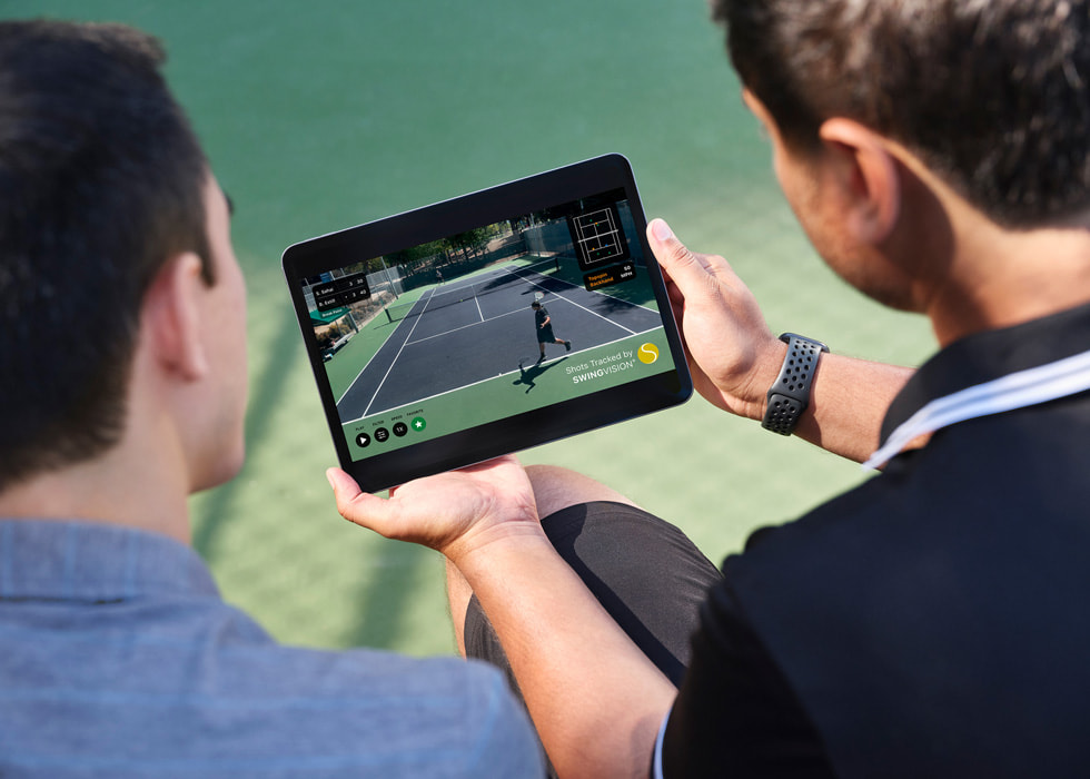 Sahai tient un iPad montrant la vidéo d’un match enregistré, qu’il regarde avec son adversaire. 