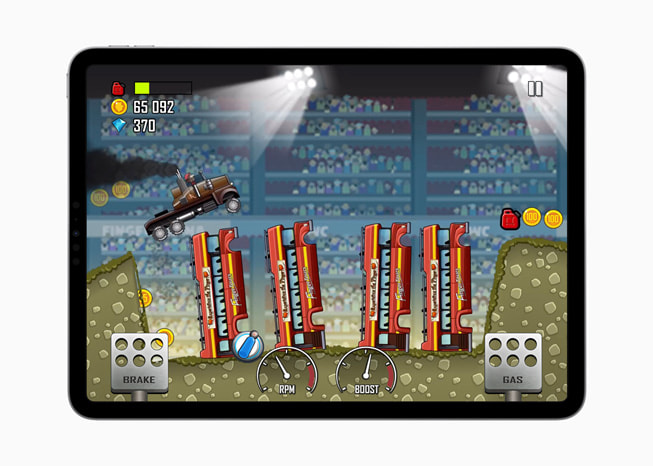 iPad Pro에서 보여주는 Hill Climb Racing+ 게임 속 몬스터 트럭이 소방차가 빠진 구덩이 위를 뛰어넘는 장면의 스틸컷.