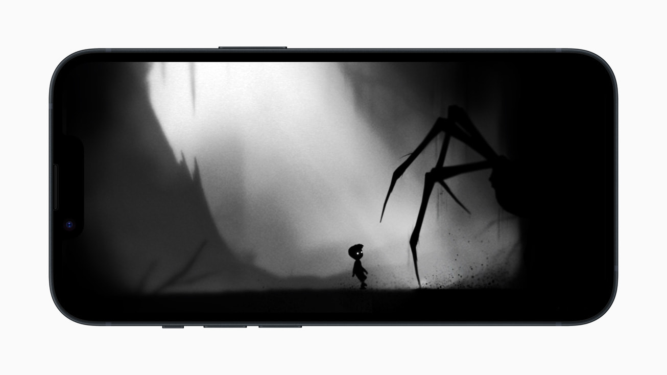 Pada iPhone 14, masih dari Limbo+ Limbo Game Playdead menunjukkan labah -labah gergasi yang bersembunyi di bayang -bayang berhampiran anak kecil
