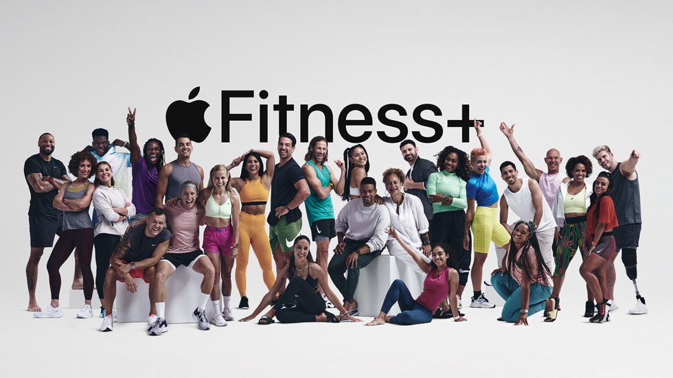 Foto di gruppo dei numerosi trainer Fitness+ davanti al logo Apple Fitness+.