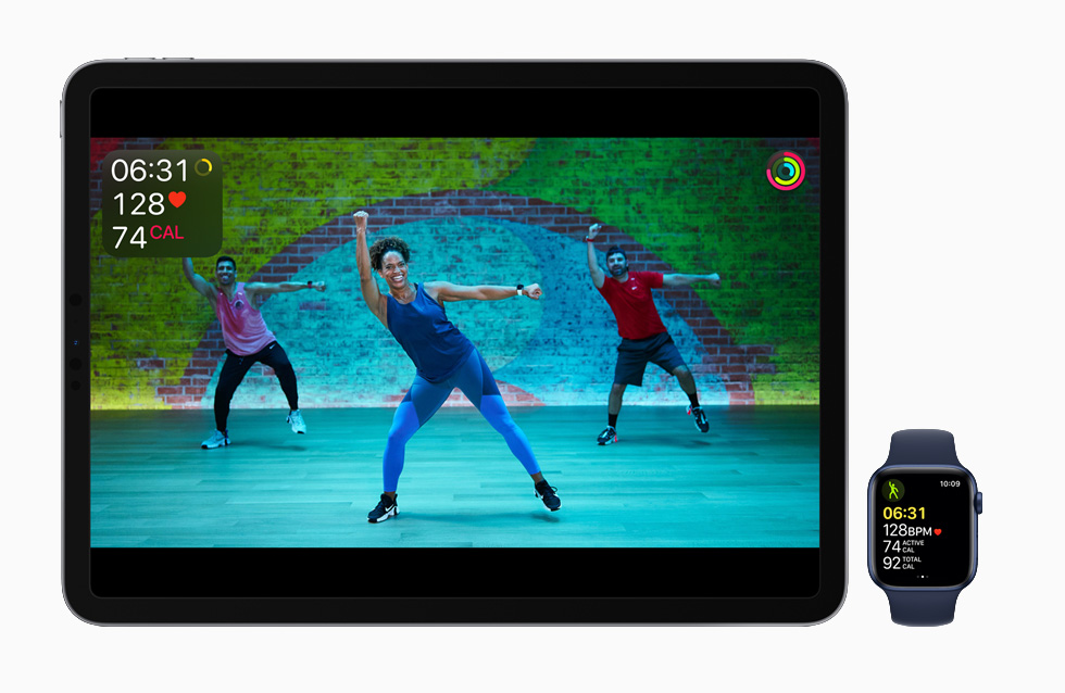 Apple Fitness+ workout displayed on iPad with animated Apple Watch metrics, with in-progress workout on Apple Watch Series 6.