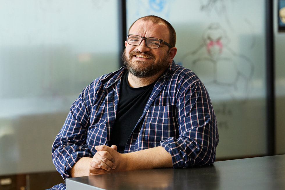 Der akademischen Dekans Tim Dailey sitzt an einem Tisch und trägt ein kariertes Hemd mit einem Button-Down Kragen über einem schwarzen T-Shirt und eine Brille.