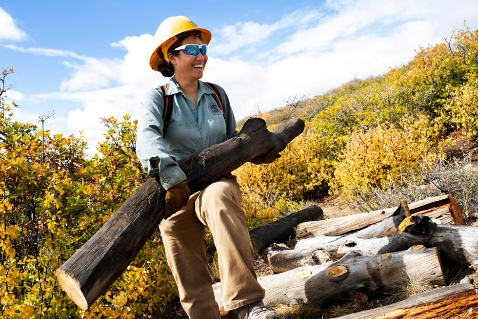 A member of the Mesa Verde Conservation group carries a log in a national park.