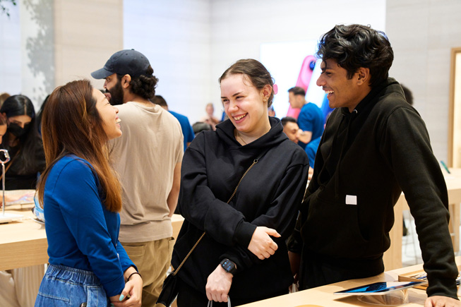 Funcionários e clientes da Apple conversam em uma Apple Store.