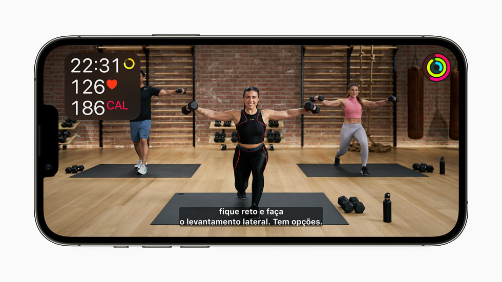 На экране iPhone 13 Pro показана тренировка Apple Fitness+ с субтитрами на португальском языке (Бразилия).