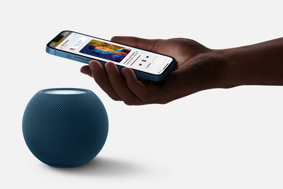 Blå HomePod mini samarbetar med iPhone för att flytta uppspelningen av musik.