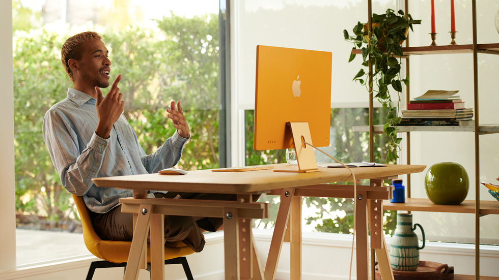 Un hombre usa su nuevo iMac naranja, instalado en la oficina de su casa.